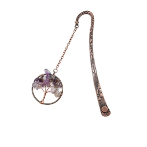 Macro detail of bronze tree of life bookmark with purple crystal stones and celestial symbols