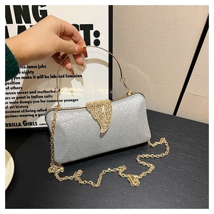 Detail of silver evening clutch featuring golden leaf clasp and metal ring handle