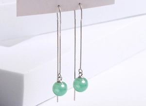 Macro shot of long silver chain earrings with polished green aventurine beads