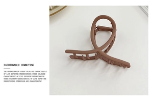Detail view of a brown matte metal hair claw clip with a stylish twisted cross design