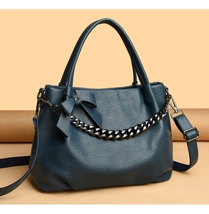 Detailed view of blue soft leather handbag with metal chain and bowknot decoration