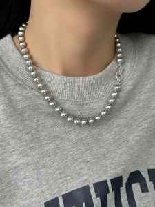 Detail of silver grey pearl necklace featuring a zircon clasp worn on the neck