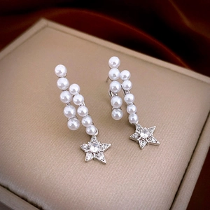 Close-up of star pearl drop earrings with zircons on a champagne jewelry box