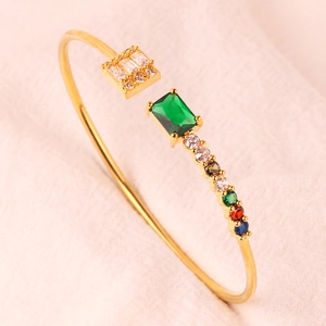 Detail van een gouden open armband met groene smaragd en veelkleurige zirkonia-stenen