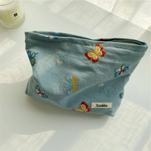 Detailed close-up of light blue cotton makeup bag with colorful butterfly embroidery