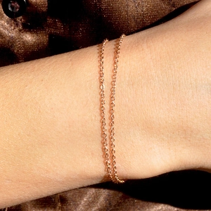 Macro shot of a minimalist gold-plated stainless steel chain bracelet on a model's wrist
