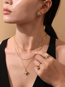 Close-up of elegant gold four-leaf clover jewelry set with sparkling zircon inlays
