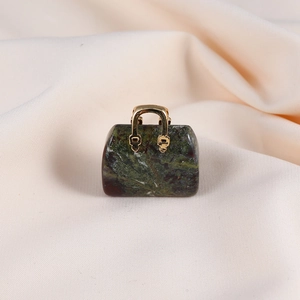 Macro detail of a bloodstone crystal handbag pendant with a golden metal handle