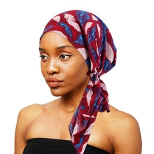 Detail view of burgundy ethnic printed turban headwrap with floral pattern knot tied on model