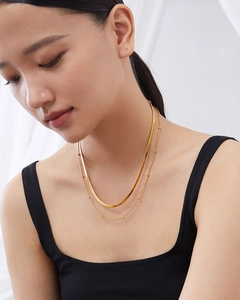 Close-up of gold titanium double layer necklace featuring snake chain and beaded link style