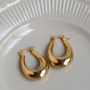 Detailed view of polished gold teardrop earrings placed on an elegant ceramic plate