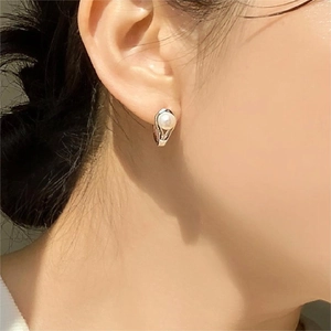 Close-up of minimalist sterling silver pearl earring worn by a model for an elegant look