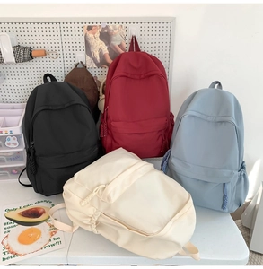 Detailansicht minimalistischer Rucksäcke in Schwarz, Rot, Blau und Beige auf einem Tisch