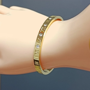 Luxury gold titanium steel bangle with roman numerals and crystals on female wrist