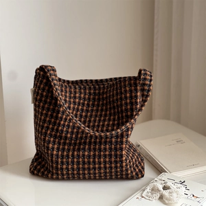 Close-up of vintage plaid tweed fabric and side label on a soft autumn shoulder bag