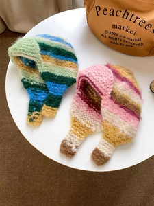 Detail of color-block knit beanie with ear flaps and ties in vibrant striped patterns