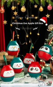 Close-up of Christmas apple gift boxes featuring snowman and panda patterns with ribbons