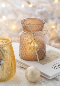 Frosted amber glass candle holder with bow and gold charm in warm bokeh lighting