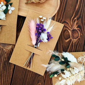 Macro shot of assorted dried flower bouquets on kraft paper greeting cards on a wood surface