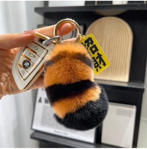 Detail of soft striped faux fur tiger tail keychain with a gold ring and yellow tag