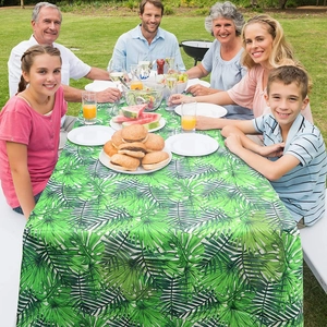 Family picnic featuring a tropical palm leaf patterned tablecloth on an outdoor wooden table