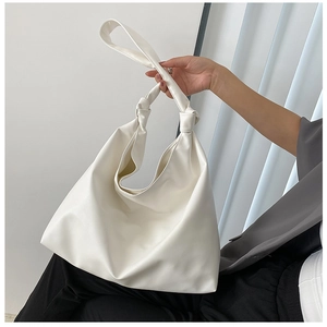 Detailed shot of large warm white hobo bag with unique knotted strap and PU leather texture