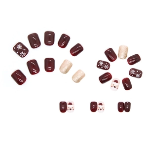 Faux ongles de Noël rouge bordeaux avec paillettes champagne et motifs de flocons de neige