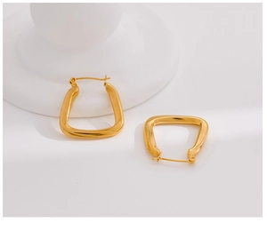 Close-up of golden U-shaped hoop earrings with polished finish and trapezoid design