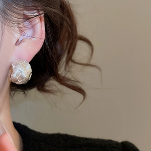 Detail of silver C-shaped stud earrings with textured weave pattern on model