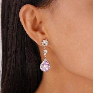 Detail of luxury teardrop earring with purple stone and crystals on female model
