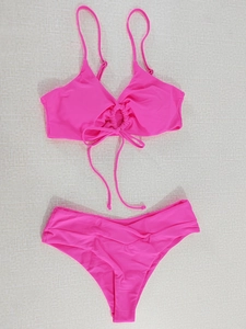 Detailed flat lay of a hot pink two-piece bikini with O-ring detail and pleated waist