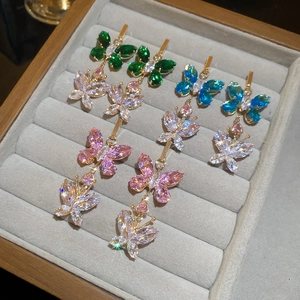 Detailed view of luxury gold butterfly and heart earrings with colorful zircons in a tray