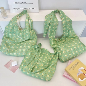 Detailed close-up of green floral canvas tote set with tie straps and square woven labels