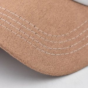 Close-up of brown suede-like cap brim with four parallel white reinforced stitching lines