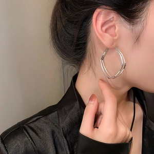 Close-up of a model wearing double-layered geometric silver hoop earrings in a modern style