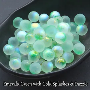 Close-up of emerald green frosted glass beads with gold glitter on a black tray