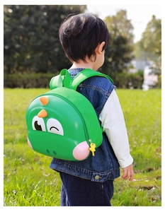 Detail of green dinosaur eggshell backpack showing adjustable straps on toddler outdoors