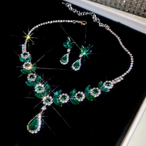 Macro shot of luxury silver jewelry set with green gemstones and shimmering diamonds