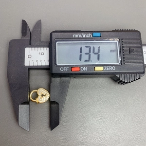 Detail shot of golden crystal heart pendant showing 13.4mm width on a digital caliper