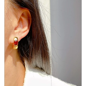 Elegant gold U-shaped earrings with oval red ruby zircons shown on a model
