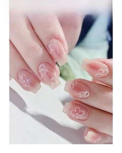 Close-up of white flower nail art stickers on long coffin-shaped nude gradient nails