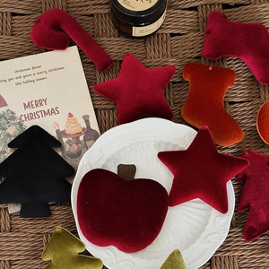 Velvet Christmas ornaments featuring stars and stockings on a woven texture mat
