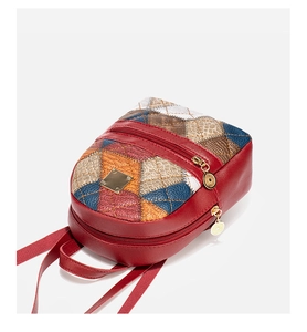 Close-up of red plaid quilted backpack featuring colorful patchwork and gold zippers