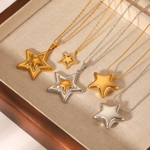 Minimalist stainless steel star pendant necklaces in gold and silver finish on linen tray