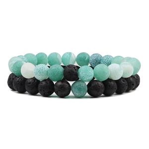 Détail de bracelets en perles de pierre de lave noire et agate craquelée verte sur fond blanc