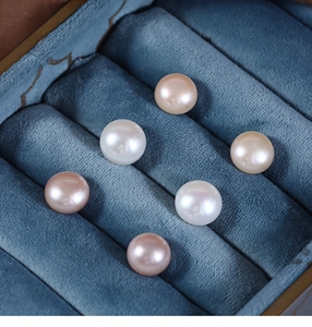 Macro shot of natural freshwater pearls in white and pink tones on blue velvet