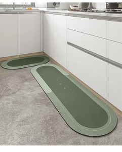 Detail of dark green oval kitchen mats set with HOME text on a modern non-slip floor
