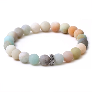 Macro view of multi-color natural stone beaded bracelet with textured silver metal charm
