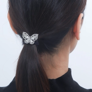 Detail of rhinestone butterfly hair tie worn on a ponytail for elegant hair styling