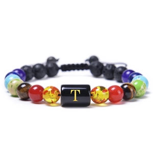 Detail of colorful volcanic stone bead bracelet featuring a gold letter T charm
